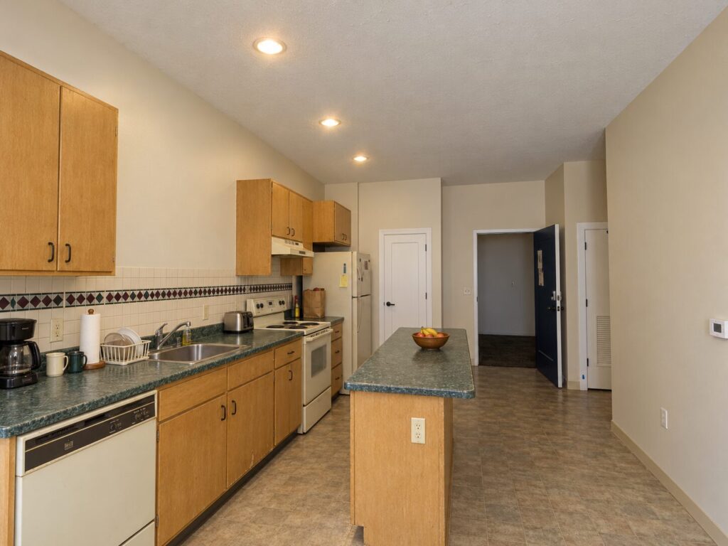 1990s St. Louis apartment kitchen before renovation with maple cabinets and connected peninsula